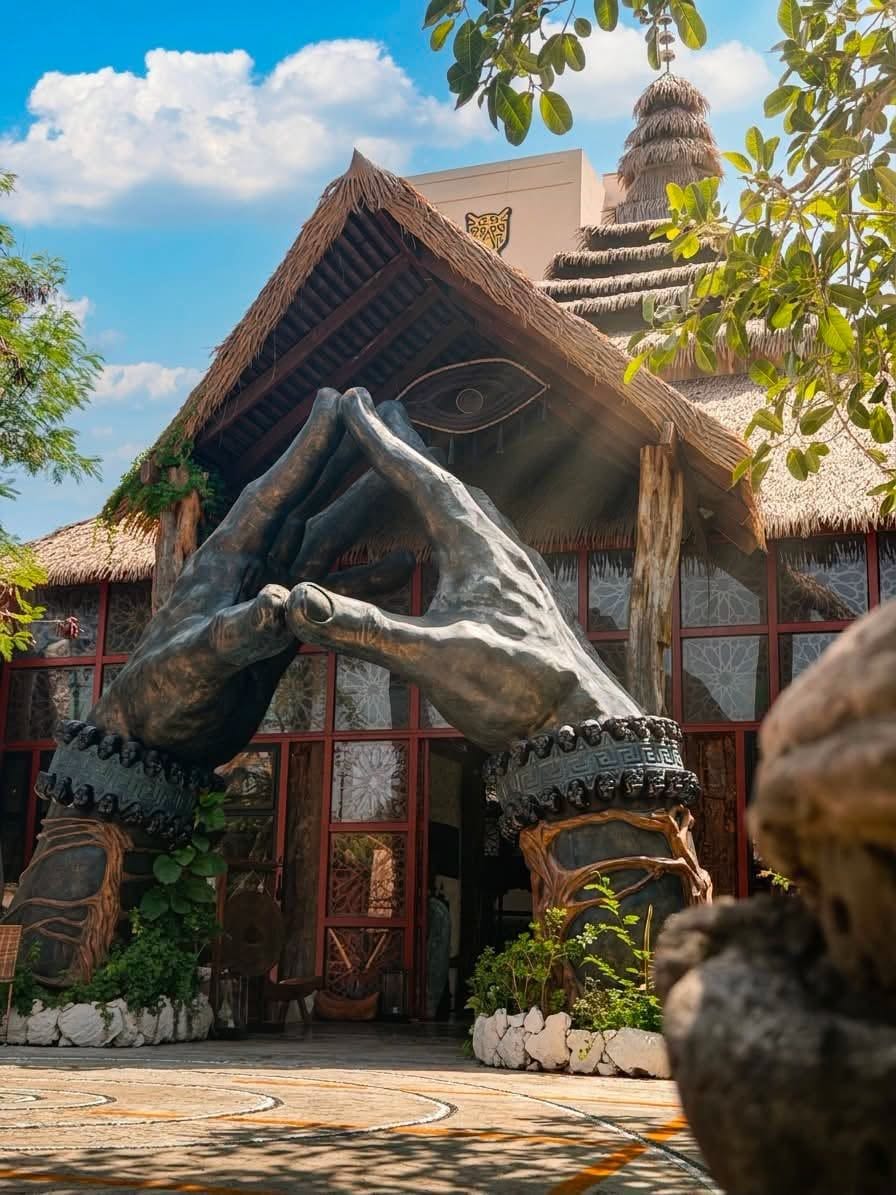 Un edificio con techo de paja, una gran escultura de piedra y un diseño tradicional.