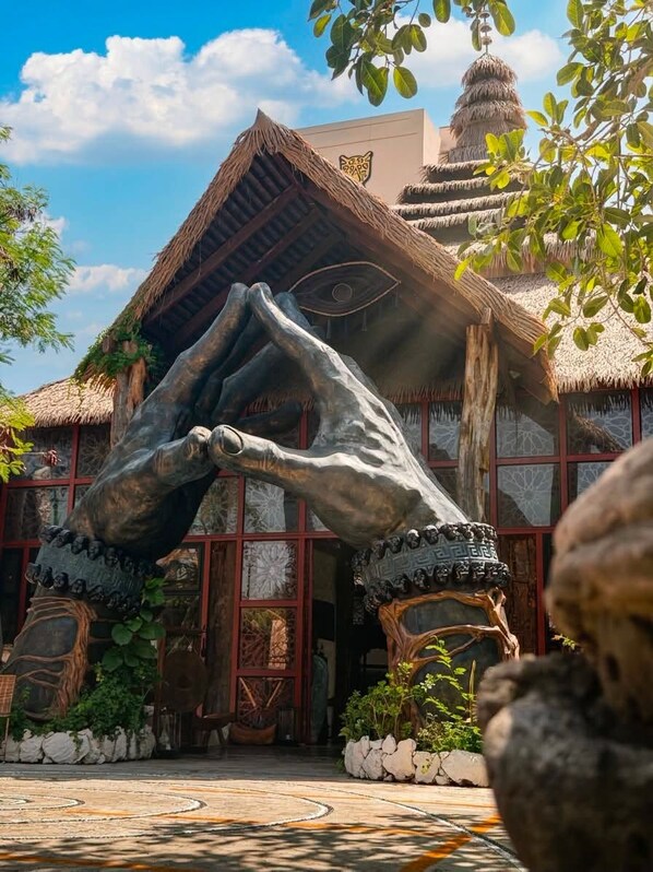 A building with a thatched roof, a large stone sculpture, and a traditional design. - Akuazul Resorts Adults Only (Cancun)