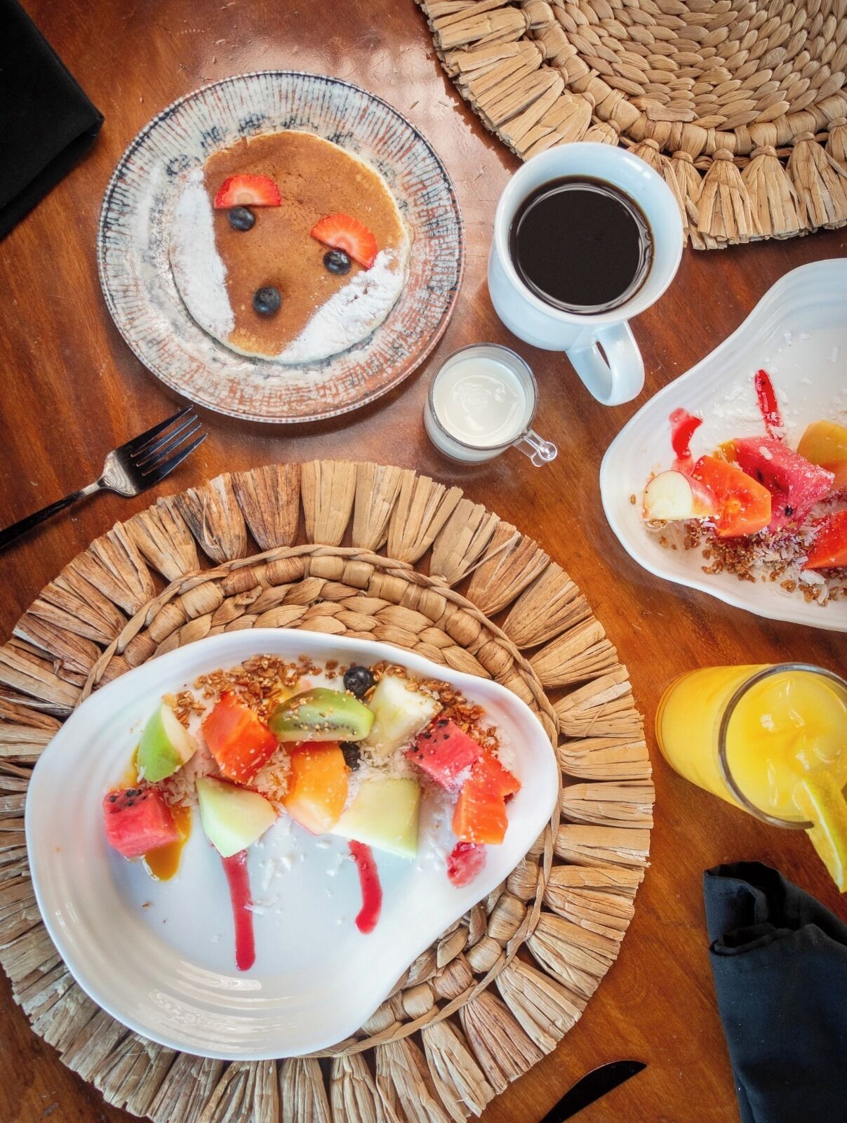 Desayuno con platos de tortitas, fruta y una taza de café.