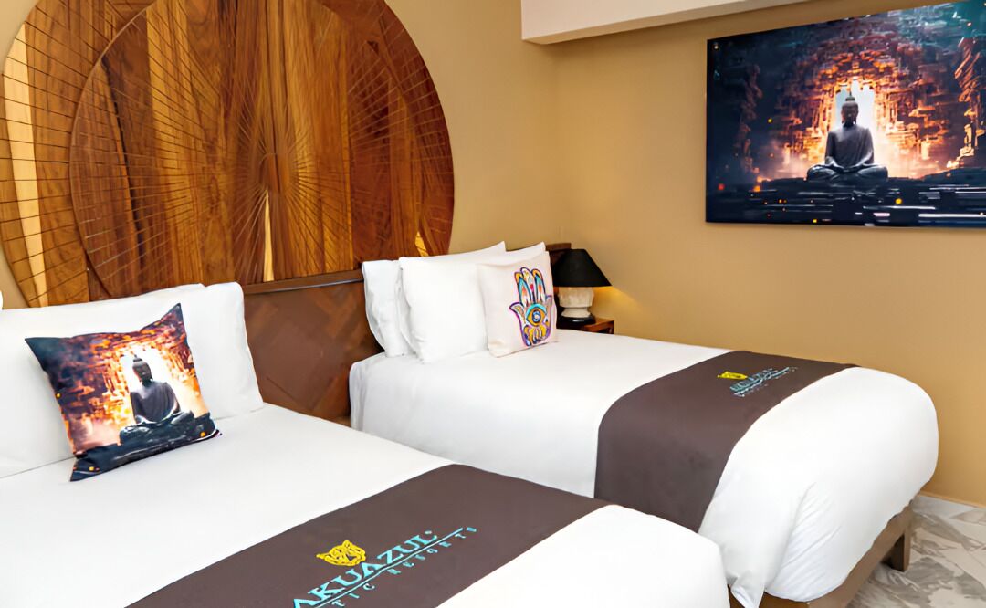 Habitación de hotel con dos camas, un cabecero grande de madera, un televisor en la pared y una estatua de Buda.