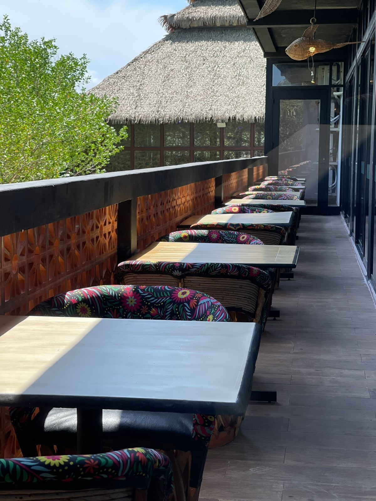 A covered outdoor seating area with thatched roofs and wooden tables and benches.