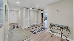 A modern interior with a mirrored closet, a glass-top table, and a view of a balcony.