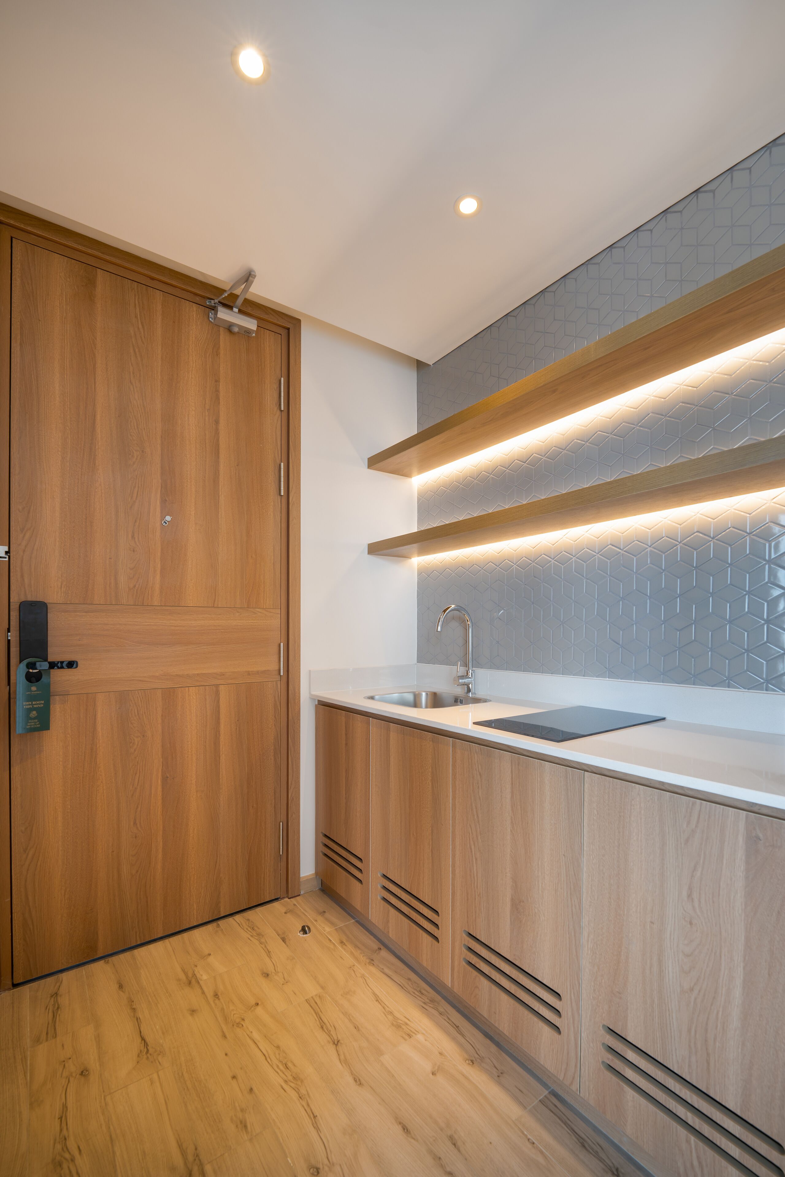 A modern kitchen with wooden cabinets, a stainless steel sink, and under-cabinet lighting.