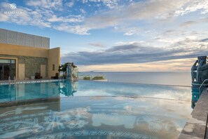 A hotel pool with a clear view of the sea, a stone wall with carvings, and a modern building facade. - M Continental By Mandala Phu Yen - 24hours Stay (Tuy Hoa)