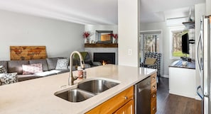 A modern kitchen with a large island, stainless steel sink, and wooden cabinets.