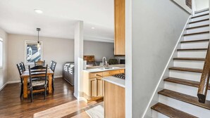 Eine moderne Küche mit Holdekor, eine Essecke mit einem Holztisch und -stühlen sowie eine Treppe mit Holzstufen.