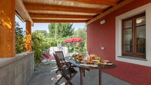 An outdoor dining area with a table set for breakfast, surrounded by chairs and a red umbrella. - Beautiful private villa with private pool, WIFI, pets allowed and panoramic view, close to Viare... (Gombitelli)