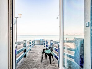 Une vue d’une promenade en bord de mer, avec un banc et une porte donnant accès à la mer.
