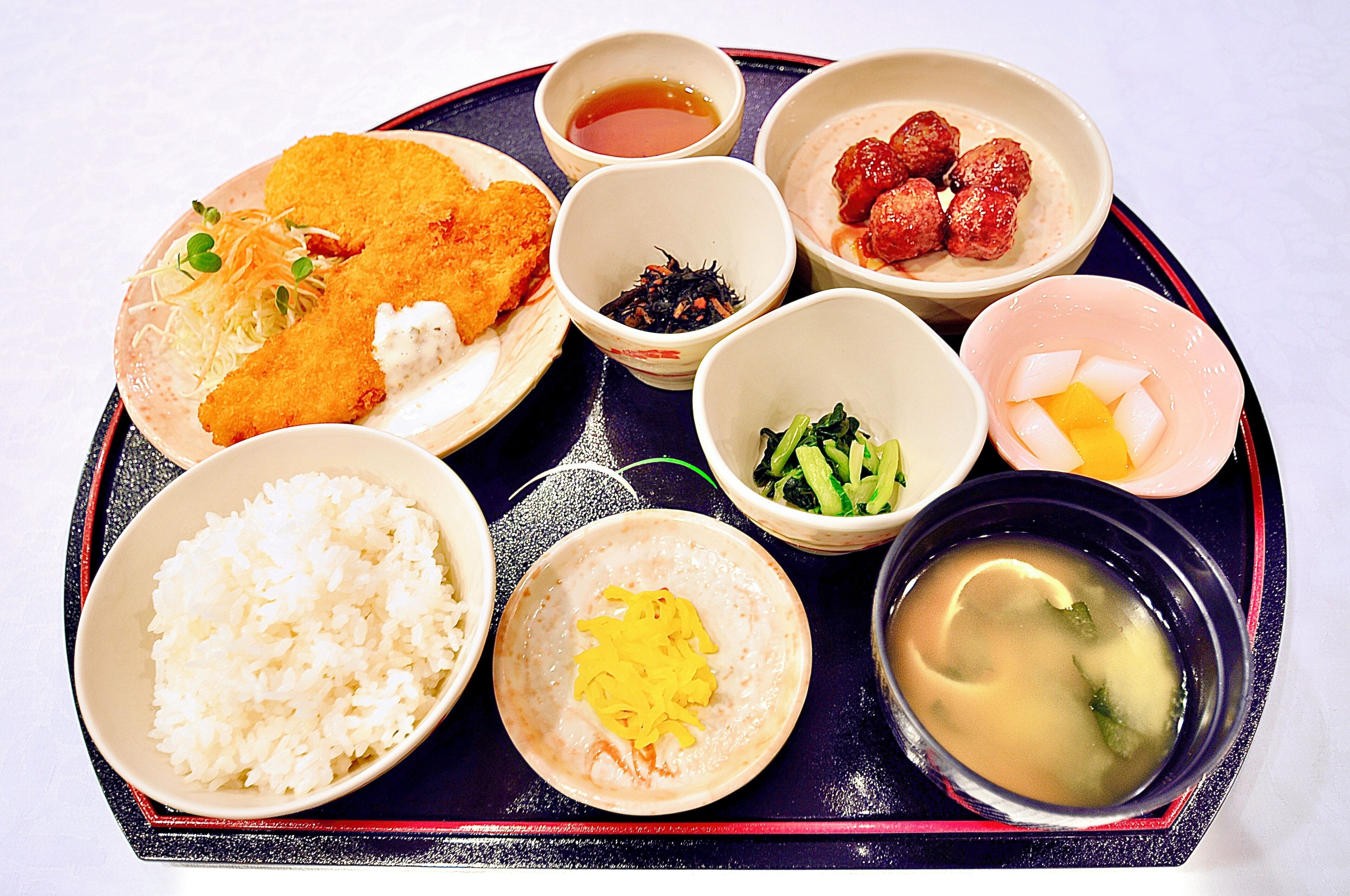 A tray with various dishes including rice, soup, and meatballs.