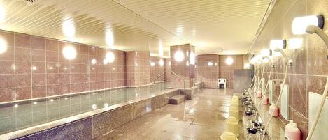 A public restroom with a long bench, multiple sinks, and hand dryers.