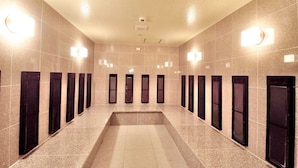 Um corredor comprido e estreito, com várias portas e luminárias nas paredes.