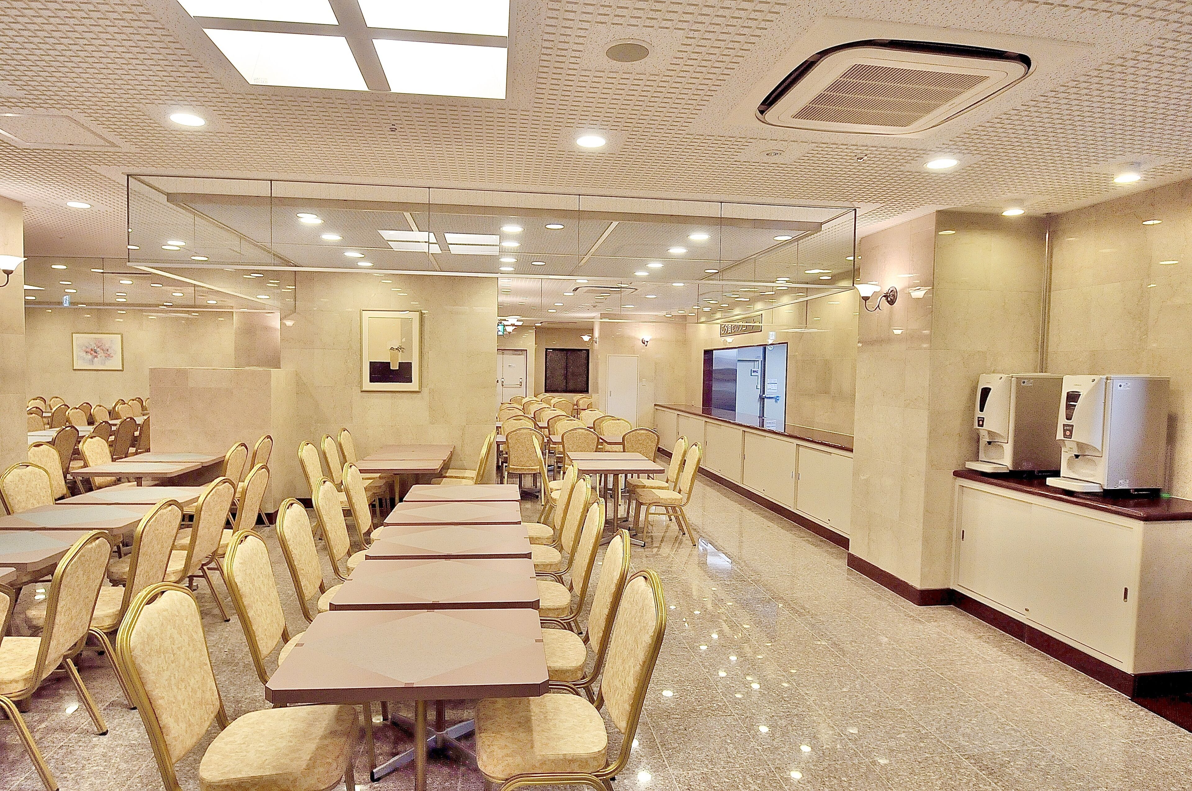 Un salón de conferencias con varias mesas y sillas, una mesa de recepción y un espejo grande en la pared.