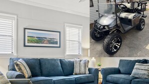 A living room with a blue sofa, a patterned rug, and a framed picture on the wall. - The Saltwater Cottage-Golf Cart & Linens Included in Ocean Lakes (Myrtle Beach)