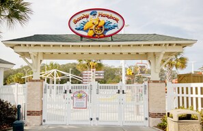 A gated entrance to Sandy Harbor with a sign above the gate. - The Saltwater Cottage-Golf Cart & Linens Included in Ocean Lakes (Myrtle Beach)