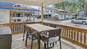 A covered outdoor patio with a wooden table and chairs, overlooking a street with houses and a parked car. - The Saltwater Cottage-Golf Cart & Linens Included in Ocean Lakes (Myrtle Beach)