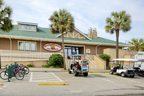 Un bâtiment sur lequel on peut lire l’inscription « Sandy Harbor Family Fun Center », ainsi qu’un parking où sont garés des vélos et des voiturettes de golf.