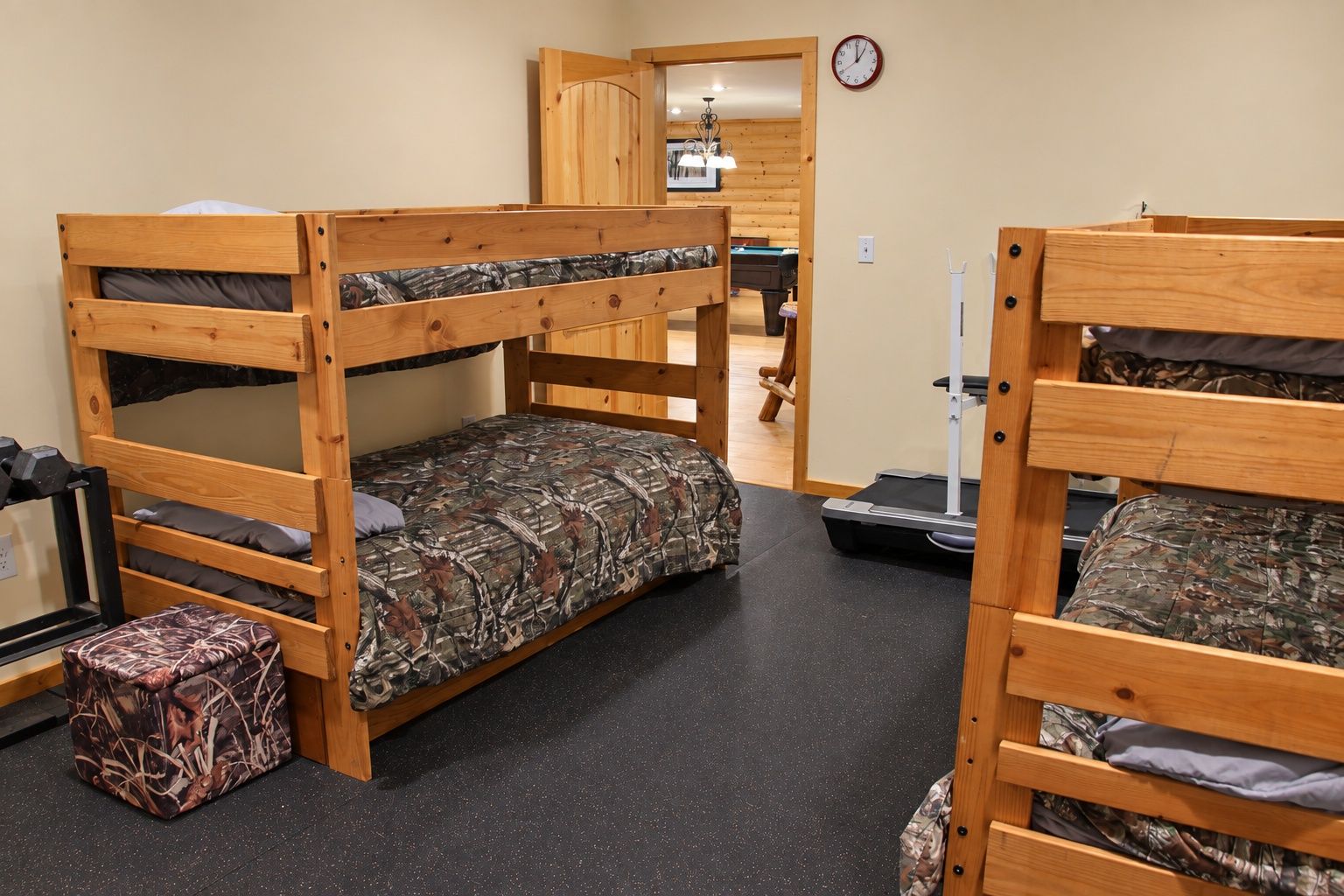 A bunk bed room with a treadmill, a clock, and a door leading to another room.