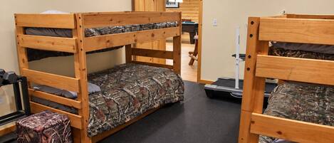 A bunk bed room with a treadmill, a clock, and a door leading to another room.