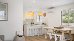 A modern kitchen with white cabinets, a wooden island, bar stools, and pendant lights. - Our Little White House -74  Padman Crescent, Middleton (Middleton)