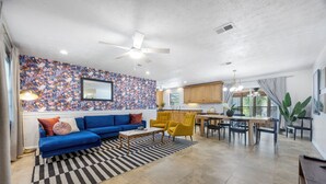 Uma sala de estar moderna com um sofá azul, cadeiras amarelas e um tapete listrado.