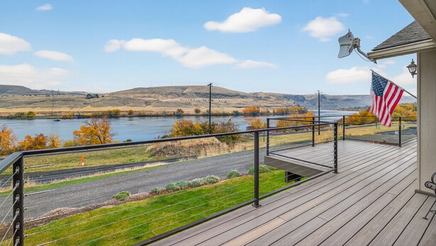 Une terrasse en bois offrant une vue sur une rivière et des collines.