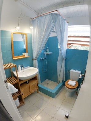 A bathroom with a shower, toilet, sink, and mirror.