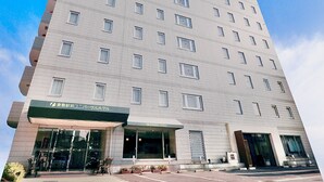 Un edificio de hotel alto con un diseño moderno, que presenta un logo verde llamativo en la parte superior.