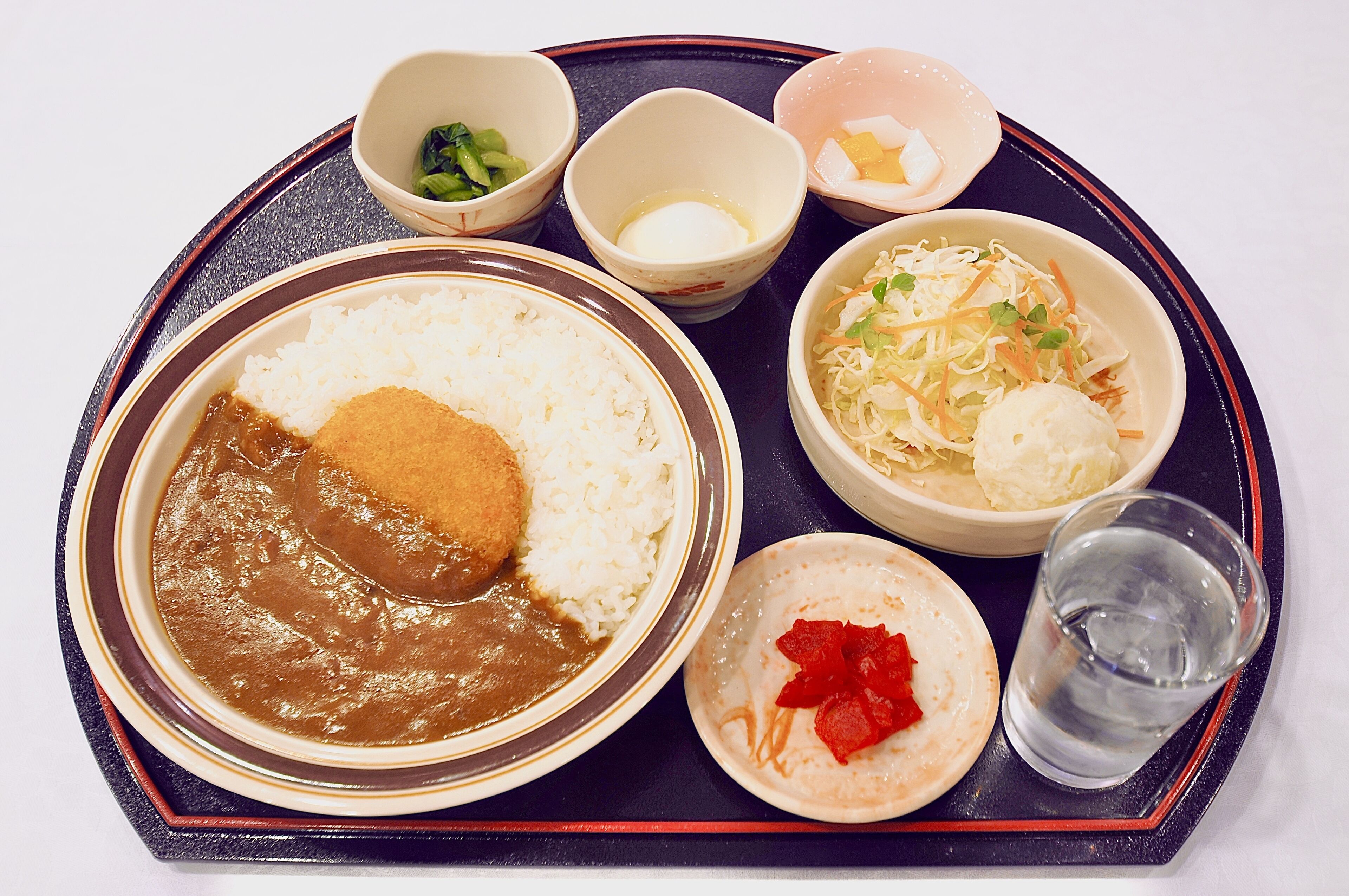 A tray with various Japanese dishes including rice, miso soup, and pickled vegetables.