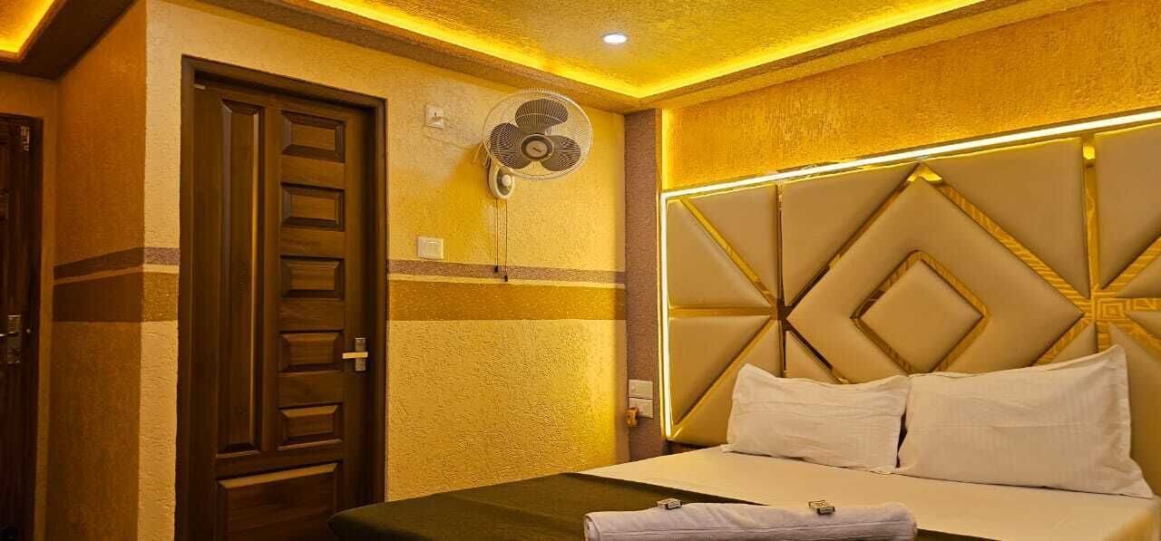 A hotel room with a bed, a wall-mounted fan, and a door.