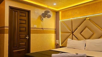 A hotel room with a bed, a wall-mounted fan, and a door.