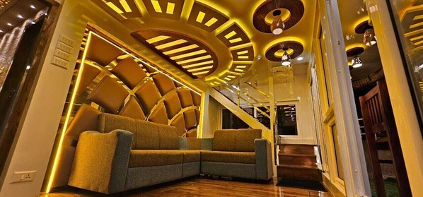 A modern interior with a sectional sofa, a staircase, and a unique ceiling design. - Royal Houseboats (Ambalapuzha)
