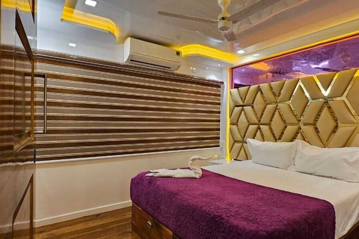 Ein modernes Schlafzimmer mit Bett, einem Kopfteil mit geometrischem Muster, einem Fenster mit Jalousien und Holzboden.