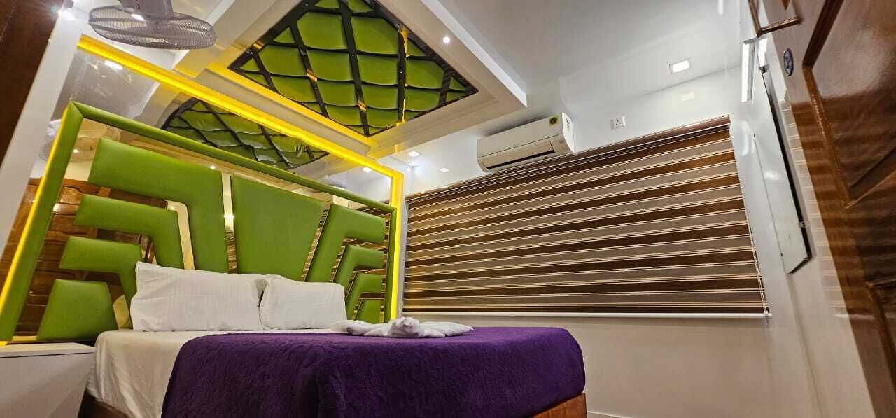 A modern bedroom with a green headboard, a purple bedspread, and a skylight above the bed.