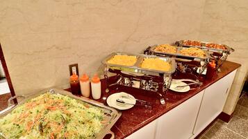 Ein Buffet mit verschiedenen Gerichten, darunter Salate und Pasta, auf einer Marmorplatte präsentiert.