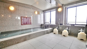 Un baño moderno con pared de granito, separador de vidrio y un ventanal grande.