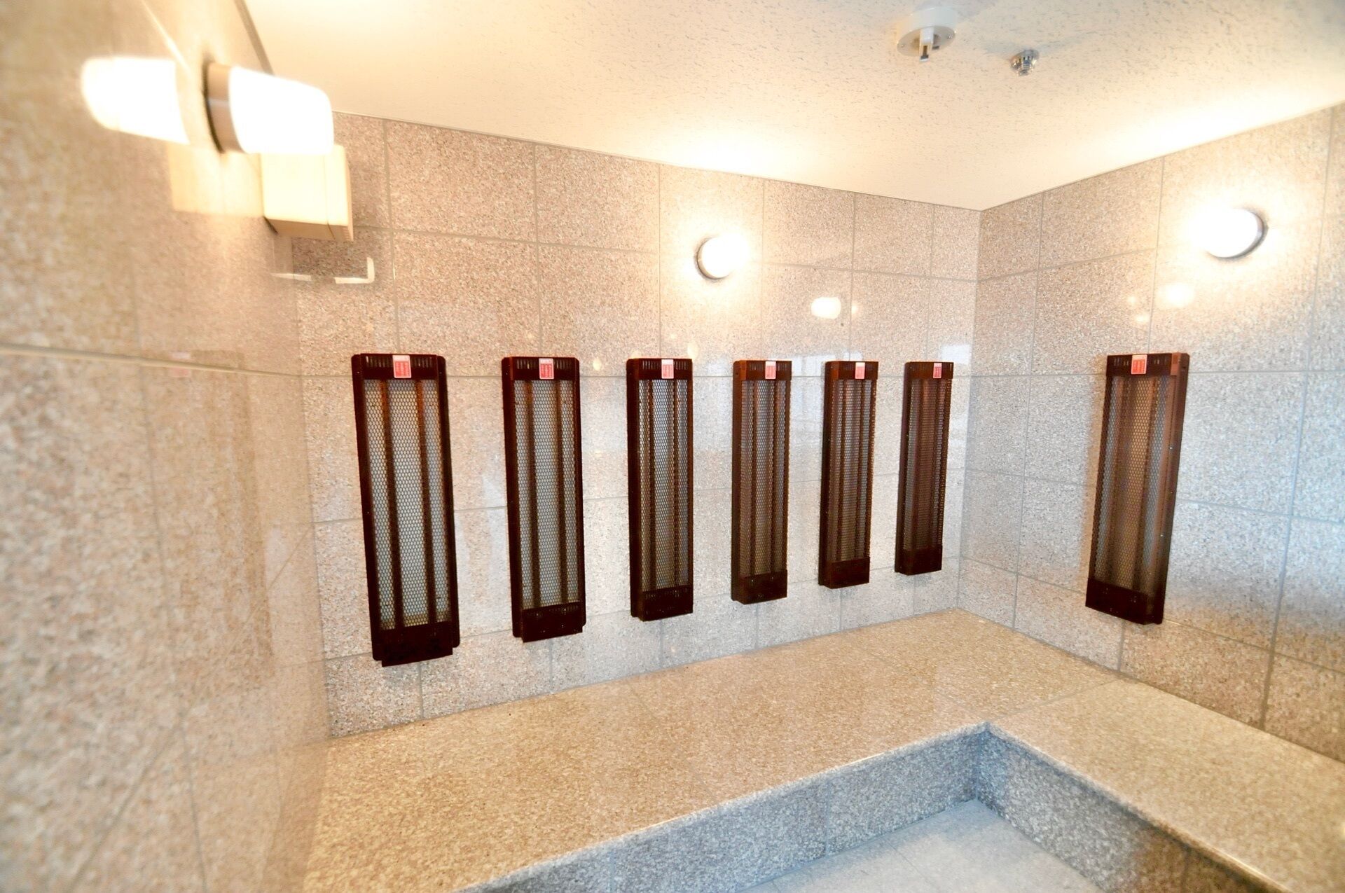 A modern bathroom with a stone wall, a rectangular sink, and six heated towel rails.