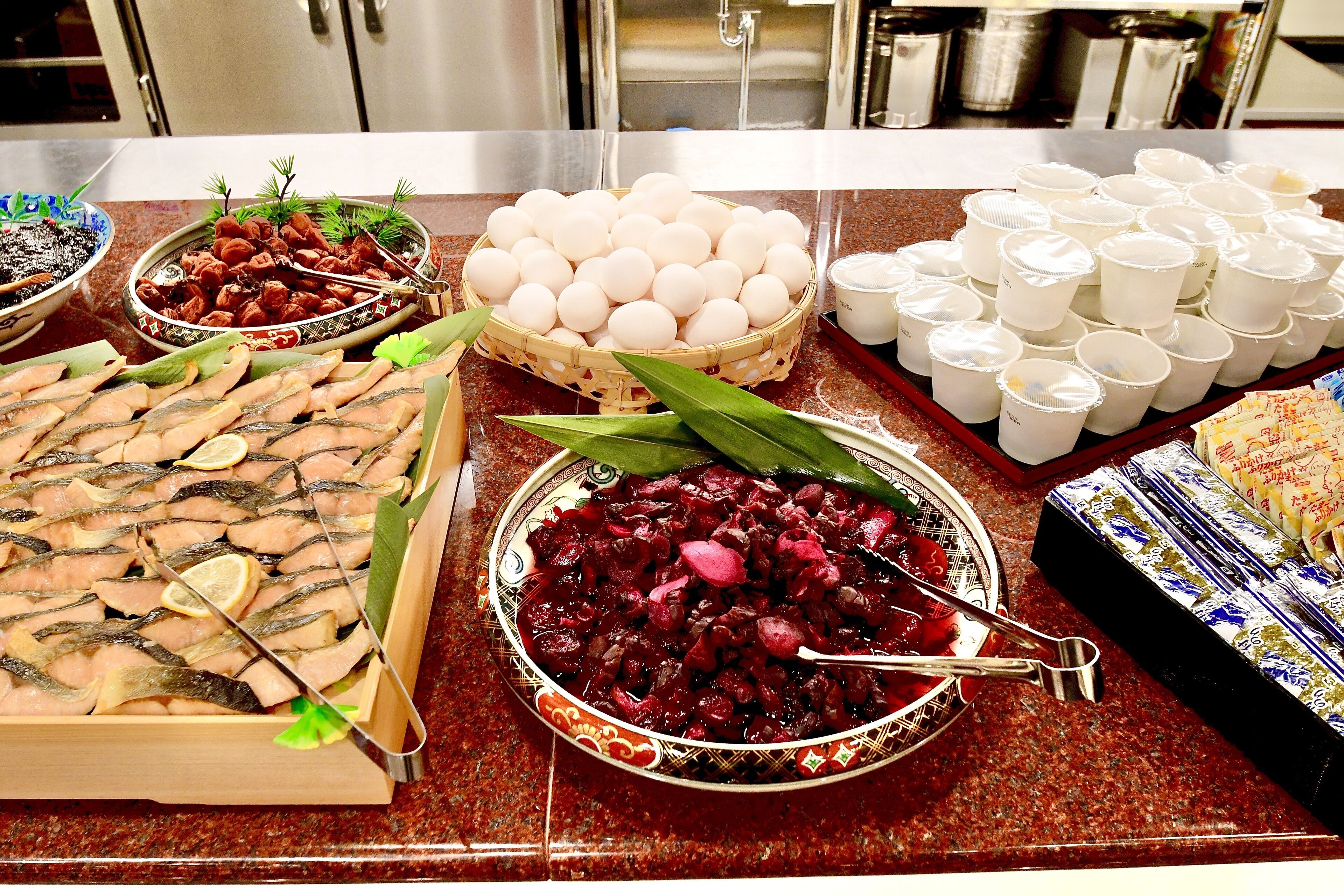 A buffet table with various dishes including fish, eggs, and a salad.