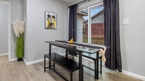 A room with a black table, a bench, a potted plant, and a painting on the wall.