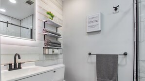 A modern bathroom with a white sink, a toilet, a glass shower enclosure, and a towel rack.