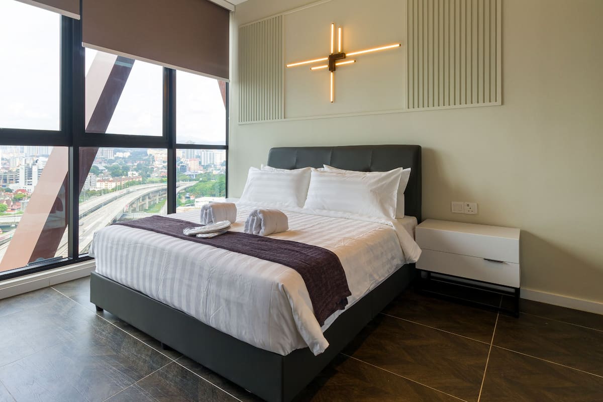 Habitación de hotel moderna con una cama grande, vistas a la ciudad y una lámpara de techo original.