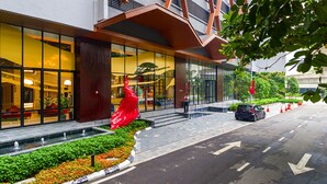 A modern building with large windows, a red sculpture, and a car parked on the street.