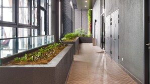 A hallway with a herringbone floor, a planter with plants, lockers, and a glass railing.