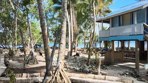 A beachfront property with a wooden structure, a pool, and a view of the sea.