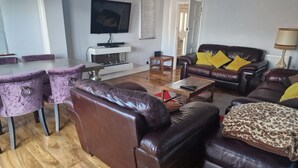 A living room with a brown leather sofa, a wooden coffee table, and a purple chair.
