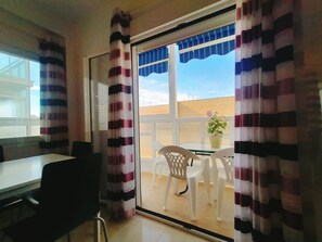 Et værelse med skydedør, et bord med stole og en potteplante.
