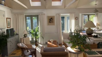 A well-lit living room with a sofa, chairs, a coffee table, and potted plants.