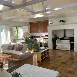 Ein geräumiger Wohnbereich mit Sofa, Esstisch und Küche mit Holzschränken.