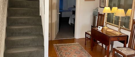 A staircase leading to a bedroom with a bed, a desk with a mirror, and a rug on the floor.