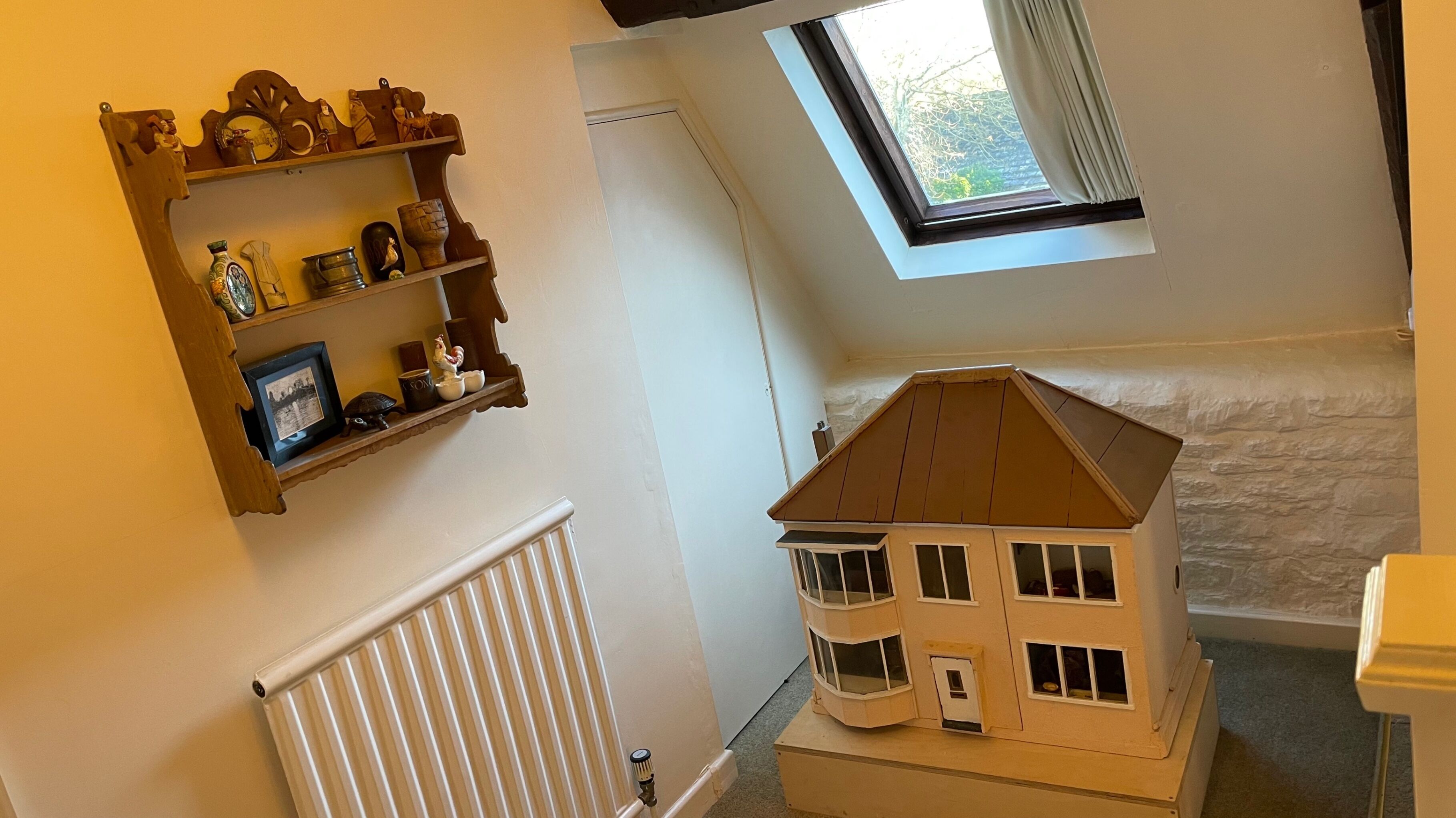 A model house with a sloped roof and multiple windows, placed on a carpeted floor.