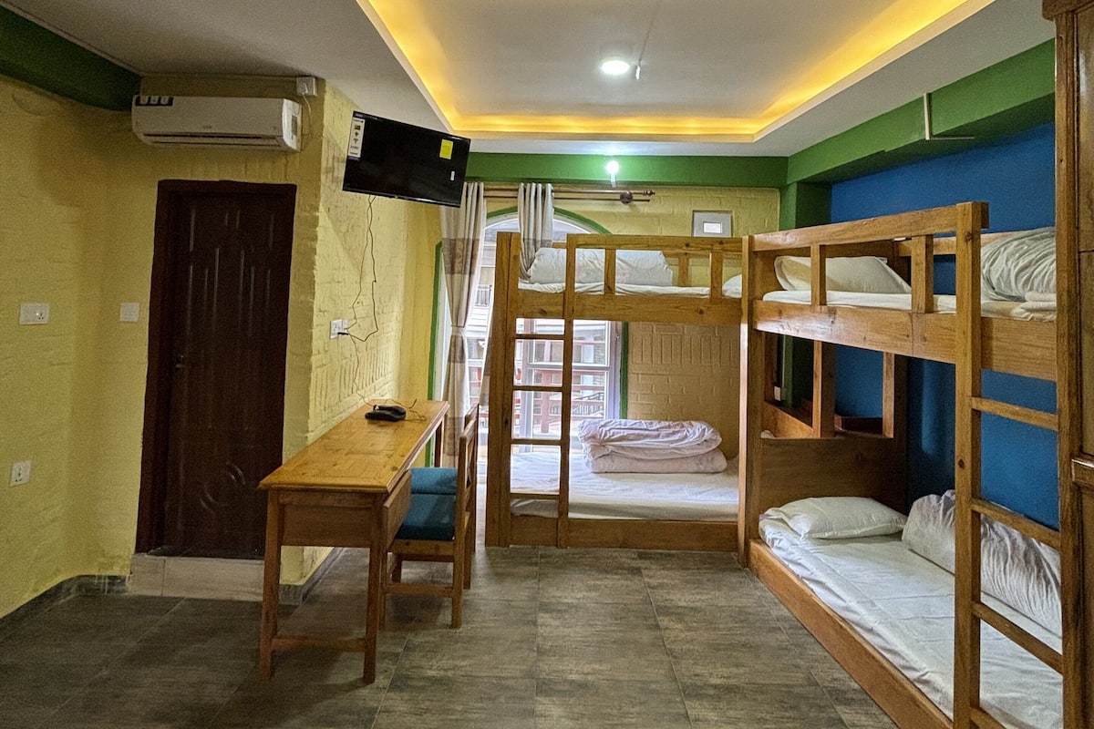 A dormitory room with bunk beds, a desk, and a chair.